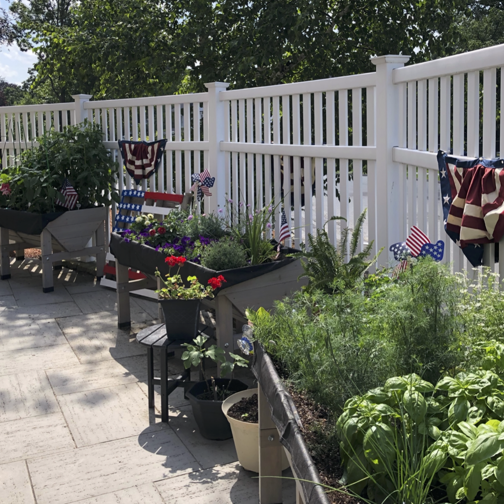 Raised garden planters with white fence and American bunting behind on sunny day